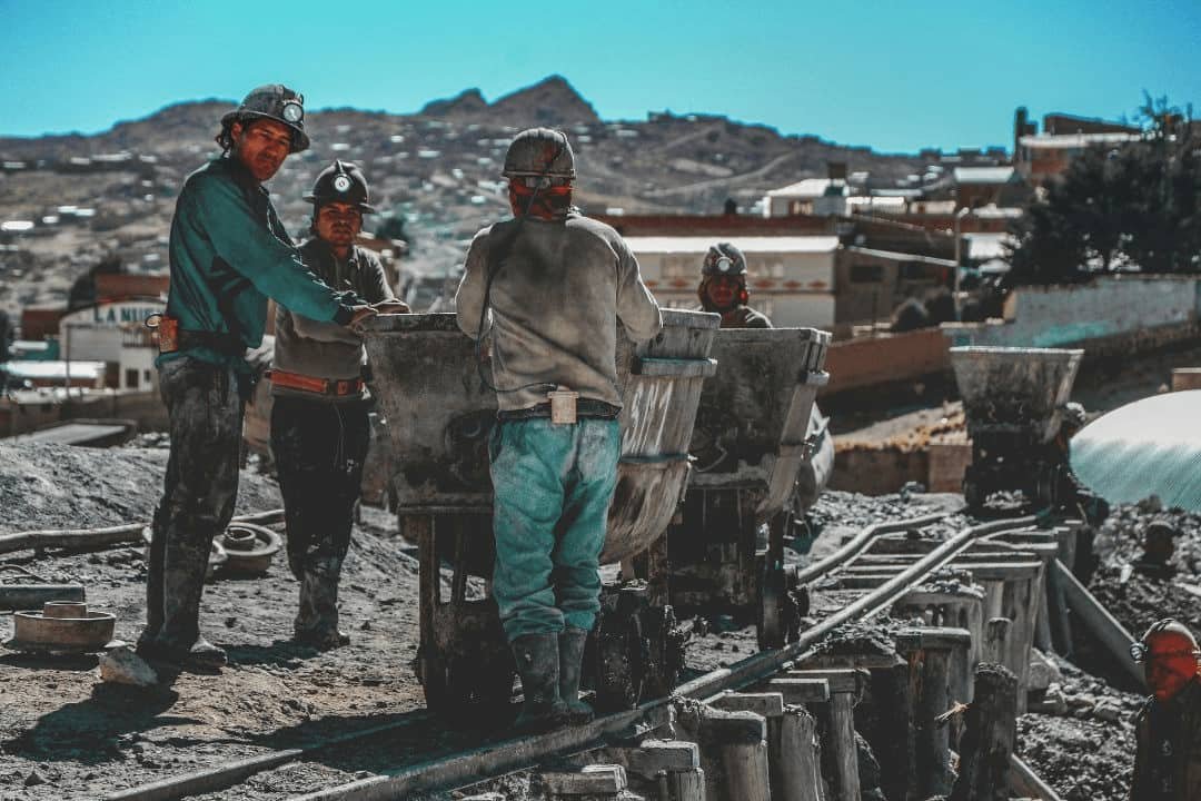 imagen de obreros mineros al lado de un carro para extraer el material del cerro rico de potosí