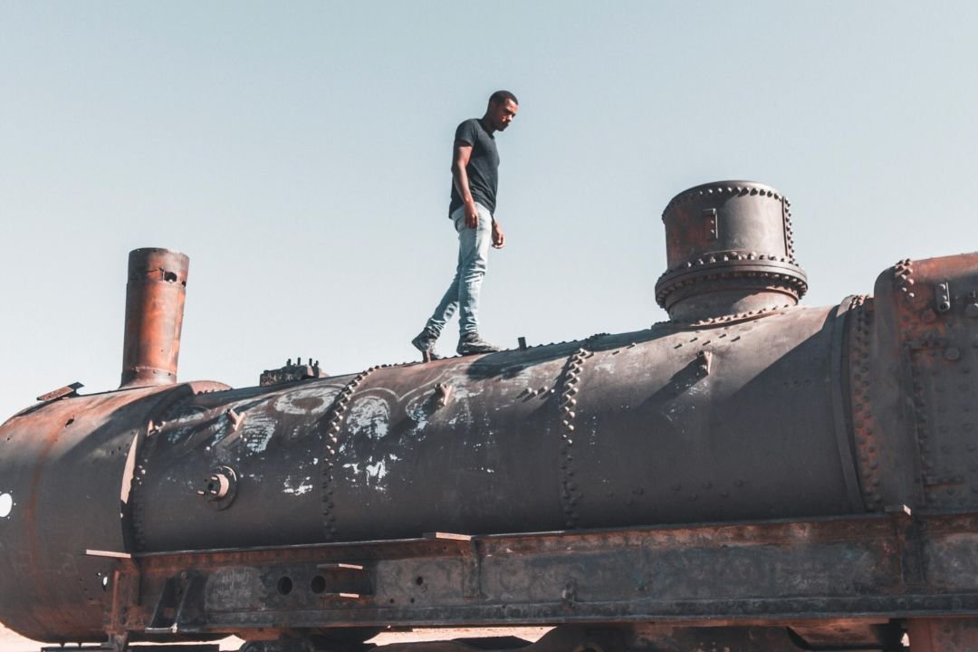 Un turista sobre una locomotora en el mitico cementerio de trenes en la localidad de Uyuni, Potosí.